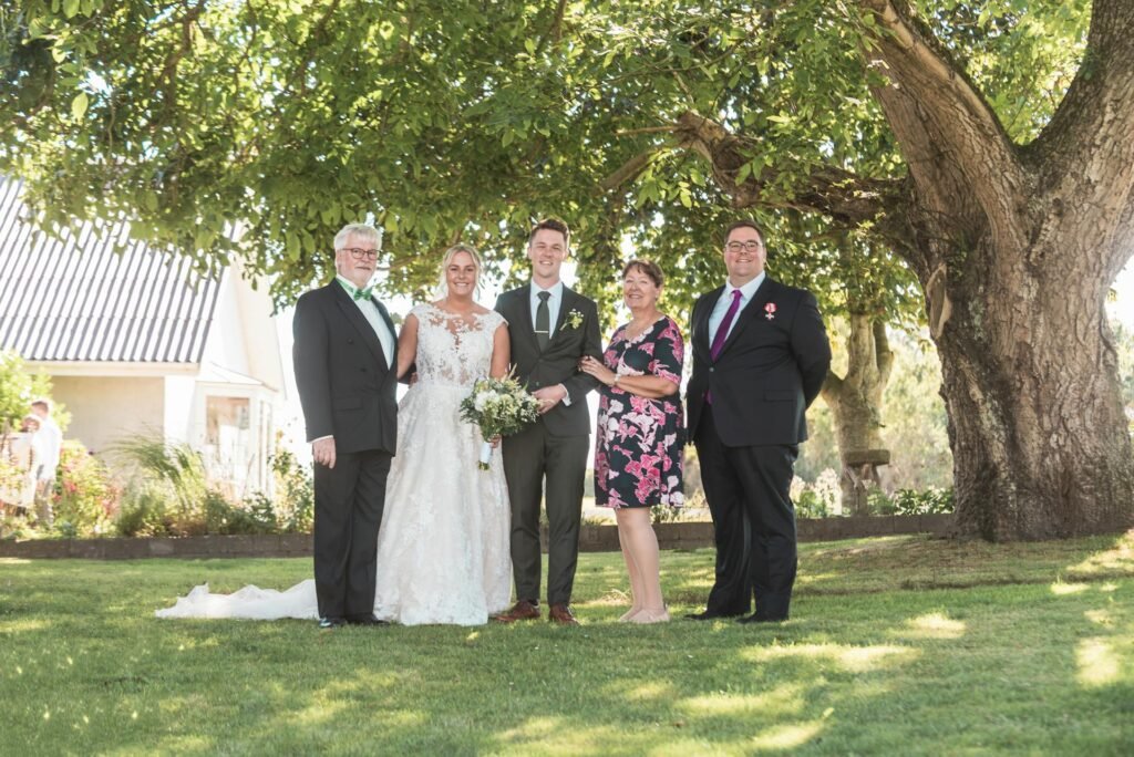Brautpaar mit Familie bei einem Gruppenfoto im Garten - Gruppenfotos Hochzeit Swissvows
